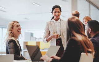 Female leader confidently addressing her team during a workplace meeting, demonstrating leadership and team engagement.