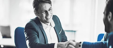 CHRO seated confidently across a conference table, engaged in strategic discussion with executive team members in a modern boardroom.