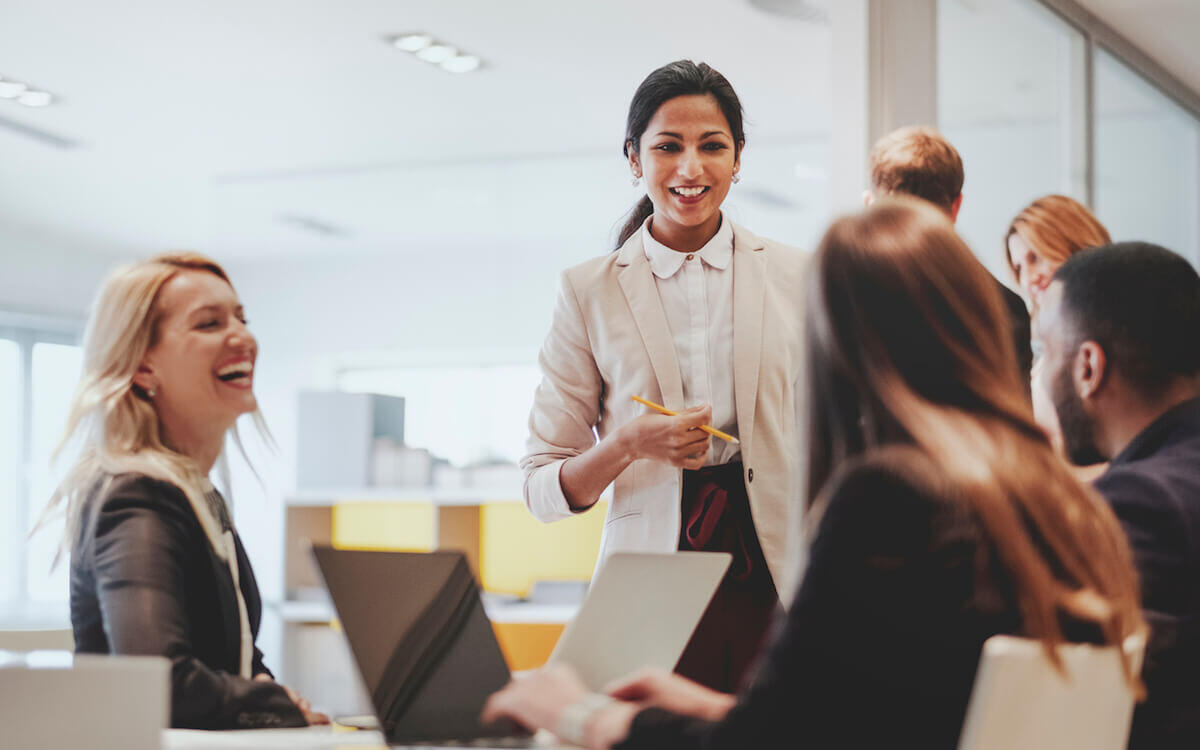 Female leader confidently addressing her team during a workplace meeting, demonstrating leadership and team engagement.