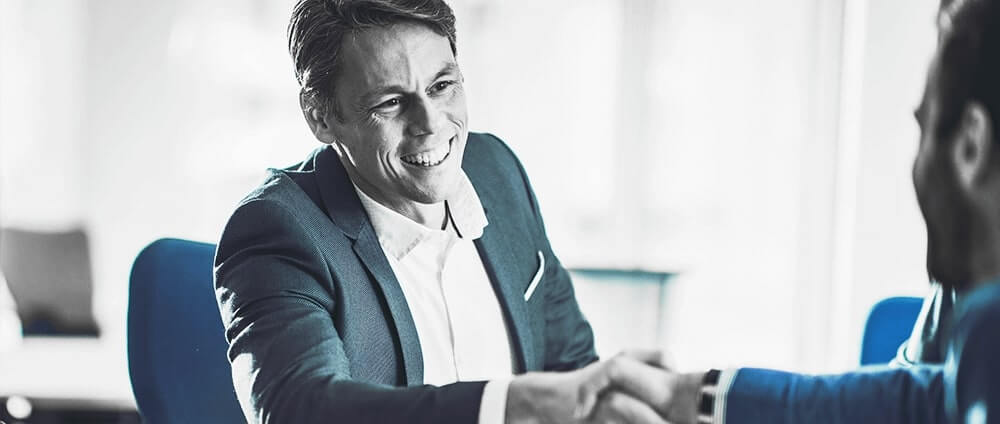 CHRO seated confidently across a conference table, engaged in strategic discussion with executive team members in a modern boardroom.